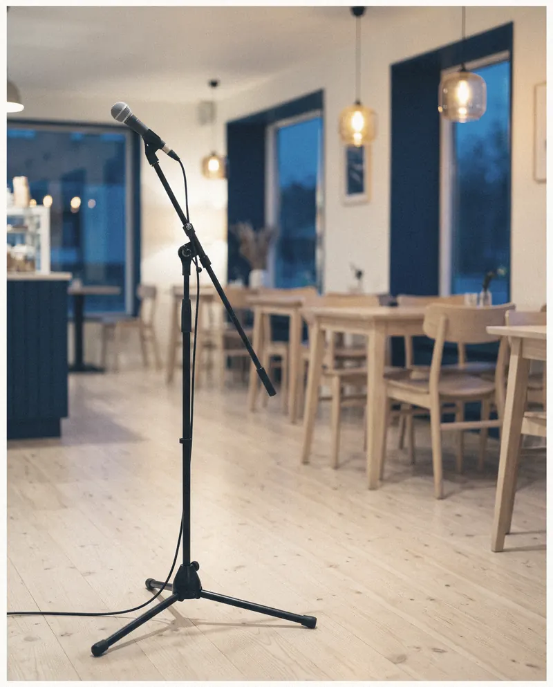 A vintage dynamic microphone on a short stand, half-lit by a warm bulb