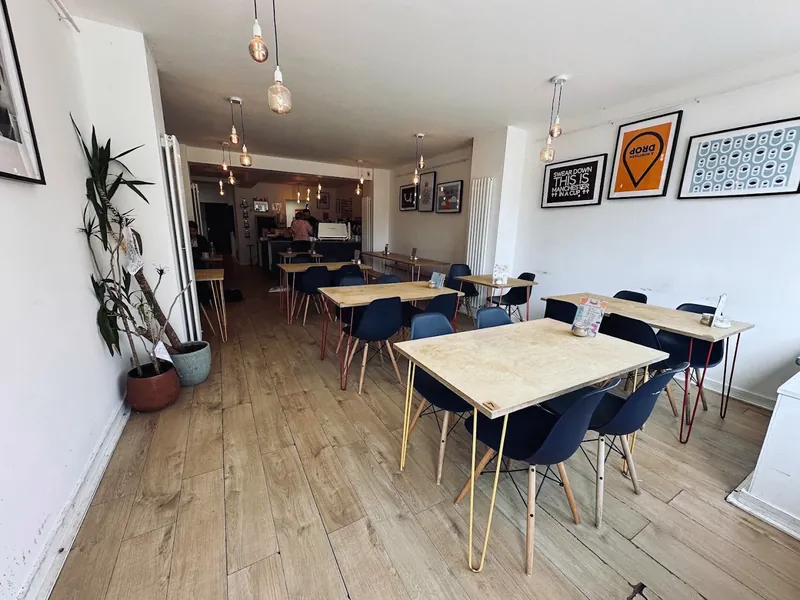 Looking down the room towards the counter: plywood tables, hairpin legs and hanging bulbs