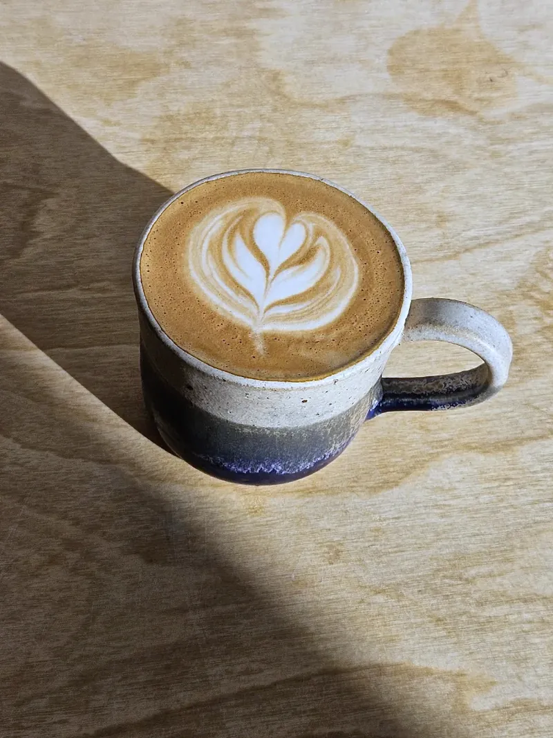 A rosetta poured into a hand-thrown, navy-dipped stoneware cup