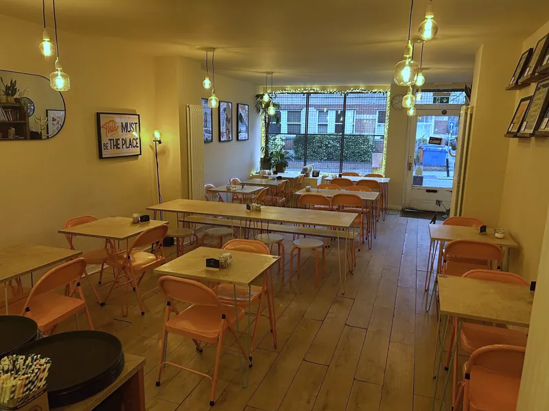 The room on Shaw Road: coral chairs, plywood tables and hanging bulbs