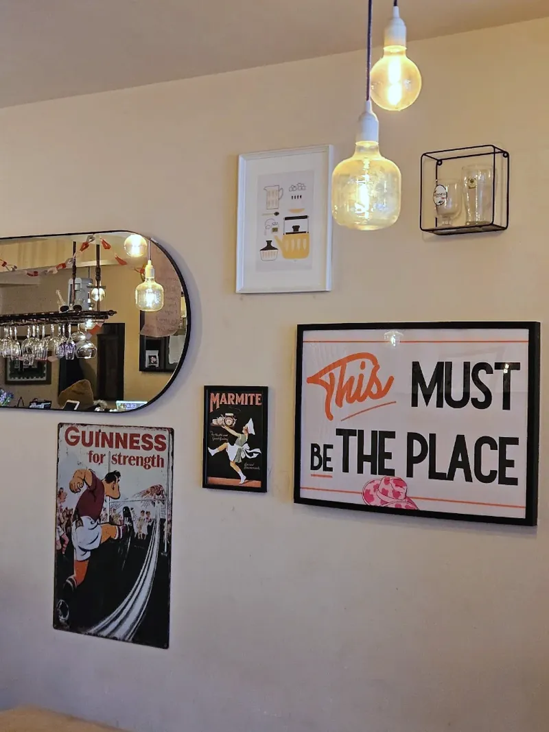 Vintage prints, an oval mirror and festoon bulbs on the wall inside Stomp